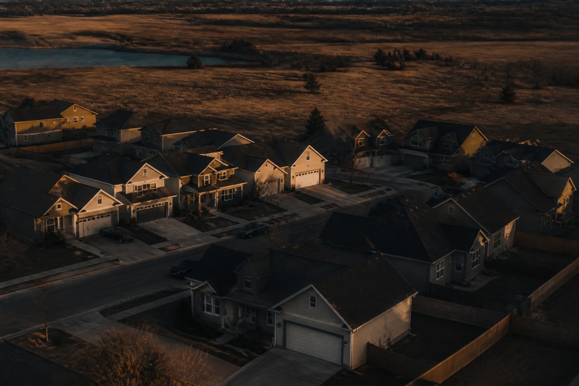 Aerial view of a residential neighborhood bordering open land at dusk